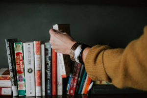 Arm of a person reaching onto a shelf to grab a book
