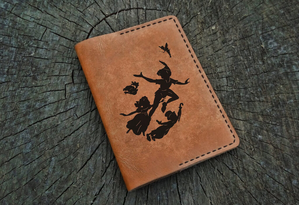 Brown leather passport cover with black silhouette image of Peter and the children flying