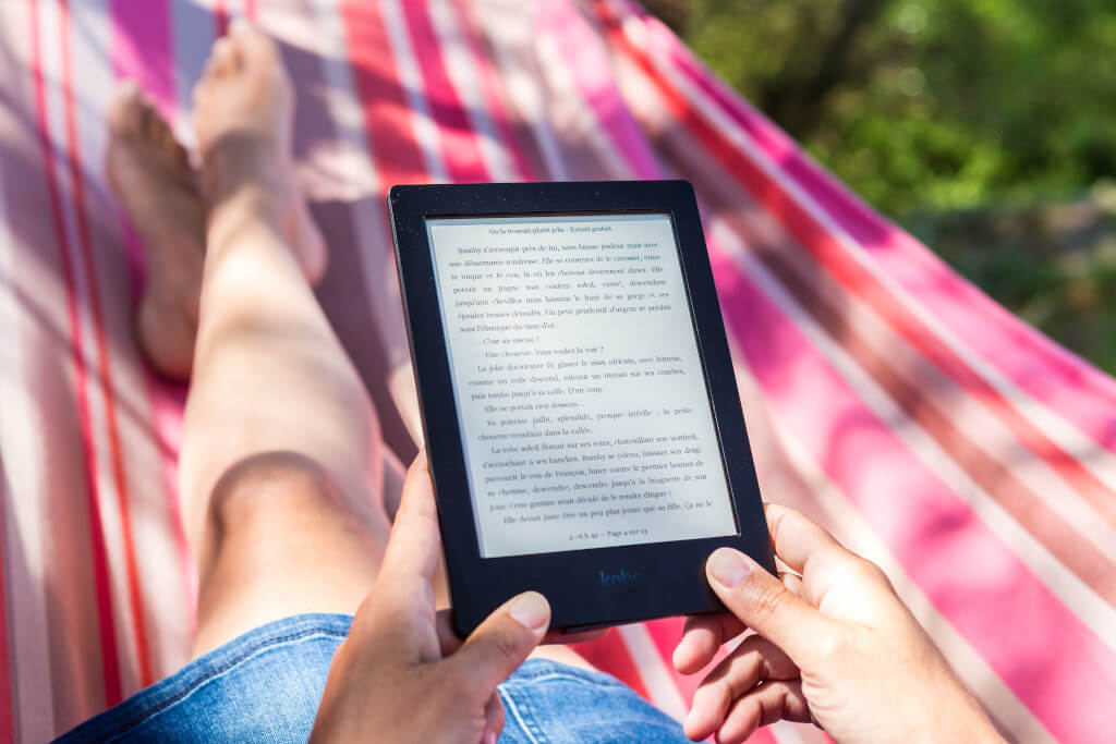 Person sitting on a pink striped hammock with a Kindle in their hands