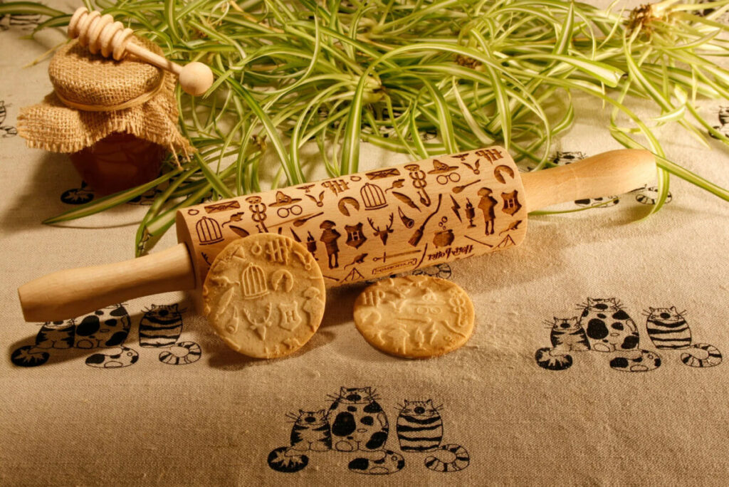 Rolling pin with Harry Potter patterns on it sitting next to cookies rolled with the Harry Potter patterns by OldCatStoreNo13