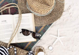Book, hat, and shells lying on the sand at the beach