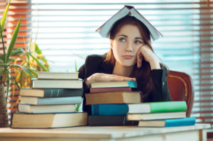 Girl with book on head and surrounded by piles of books