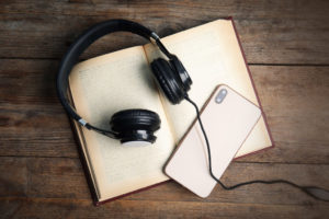 Black headphones and phone lying on top of a book
