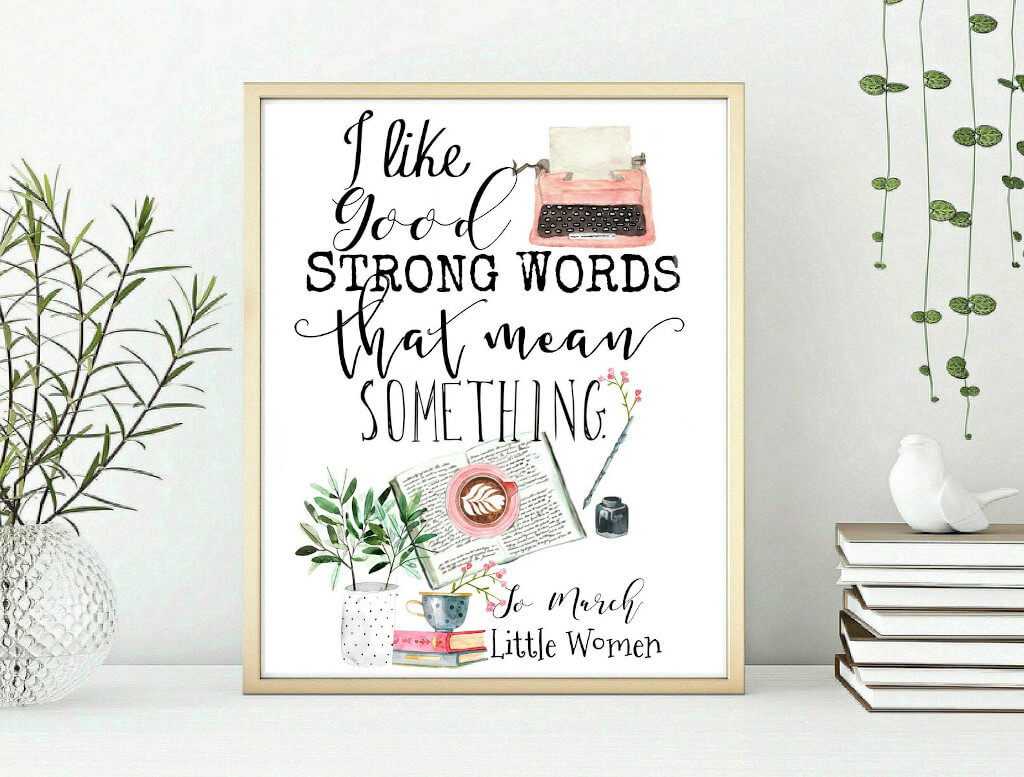 Framed poster that reads "I like good strong words that mean something - Jo March, Little Women". It also features a picture of a pink typewriter, a plant, a few books, and a coffee cup. By Shop Lucy in the Sky