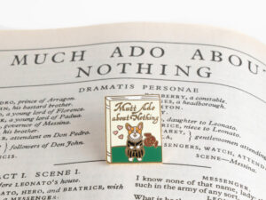 Enamel pin that has a dog on it and says Mutt Ado About Nothing by Bona Fide Bookworm