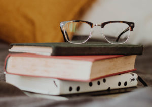 Three books stacked on top of each other with glasses sitting on top