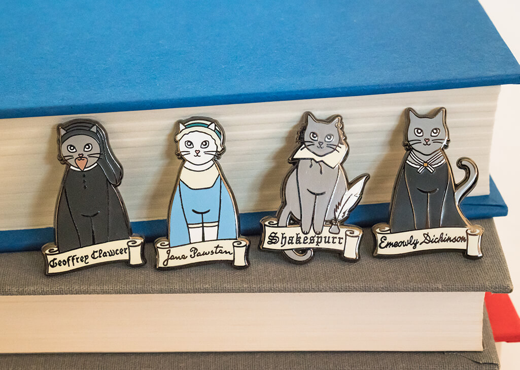 Four cat-shaped enamel pins: Geoffrey Clawcer, Jane Pawsten, Shakespurr, and Emeowly Dickinson