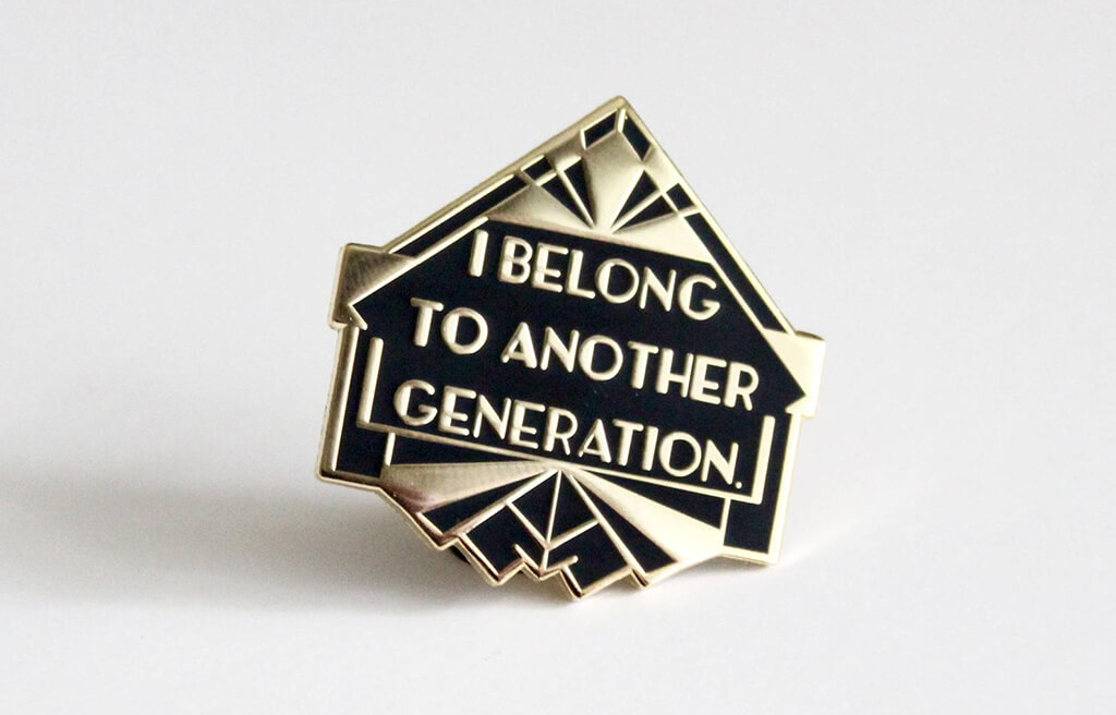 Black and gold enamel pin that reads "I belong to another generation" by The Silver Spider