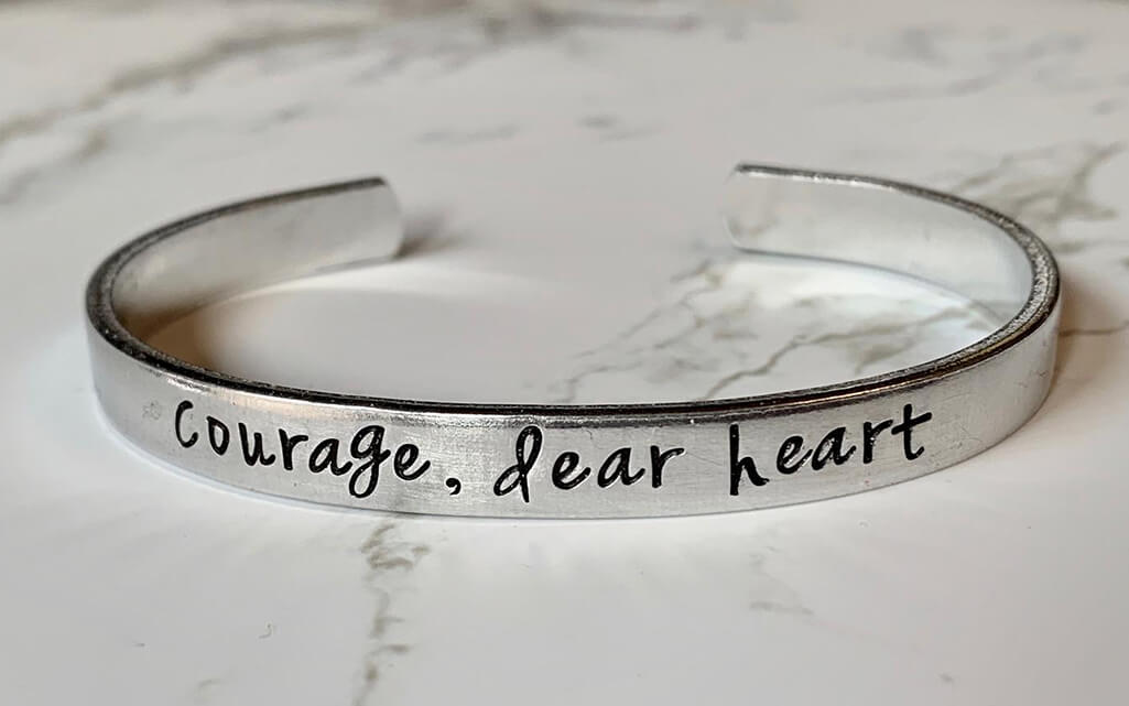 Silver cuff bracelet that reads "Courage, dear heart" by Oak Lane Studio