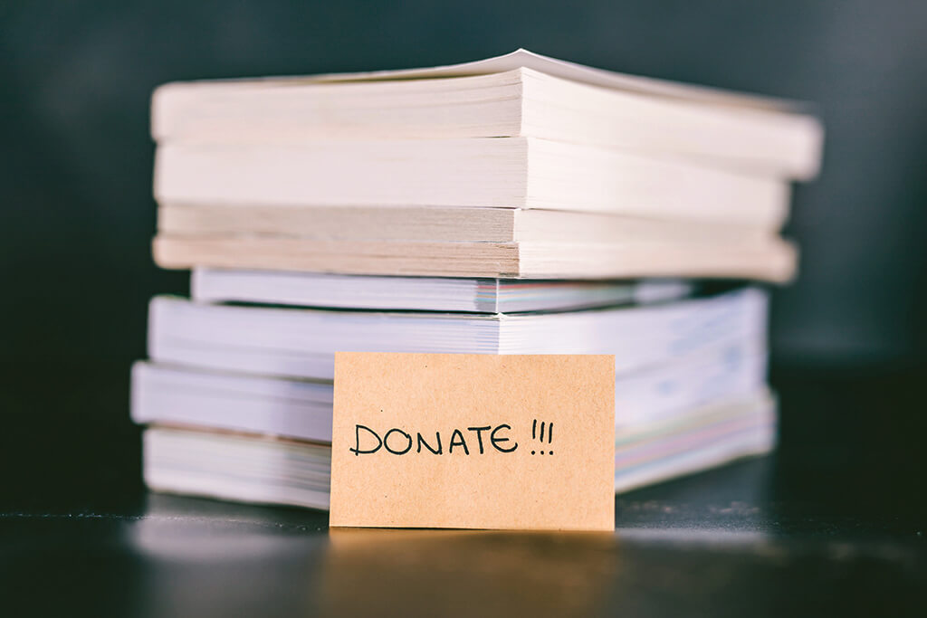 Stack of books with a little brown card in front that reads "Donate!!!"