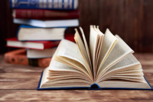 Book open with fanned pages in front of a stack of books