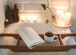 Book and tea sitting on tray in the bathtub