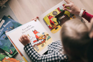 Child reading a picture book about a fox