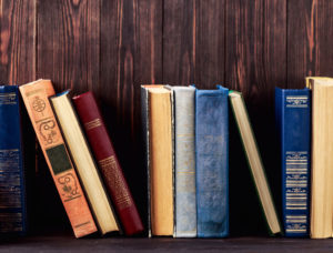Old books lined up against a wooden background