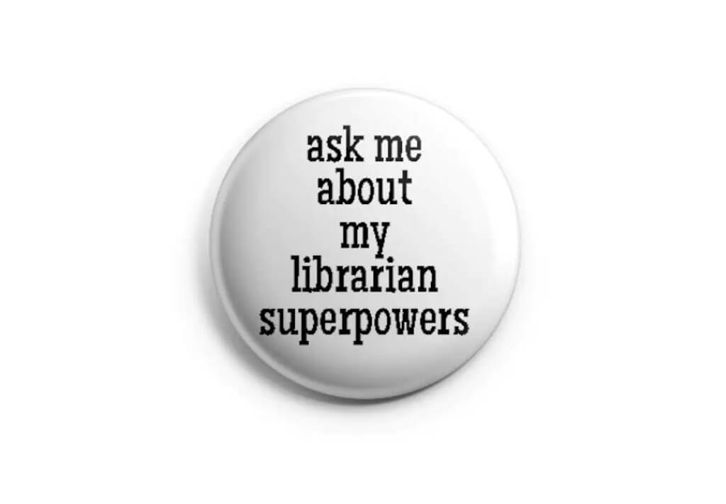 Round white button with black text that reads "ask me about my librarian superpowers" by PricklyCactusCollage