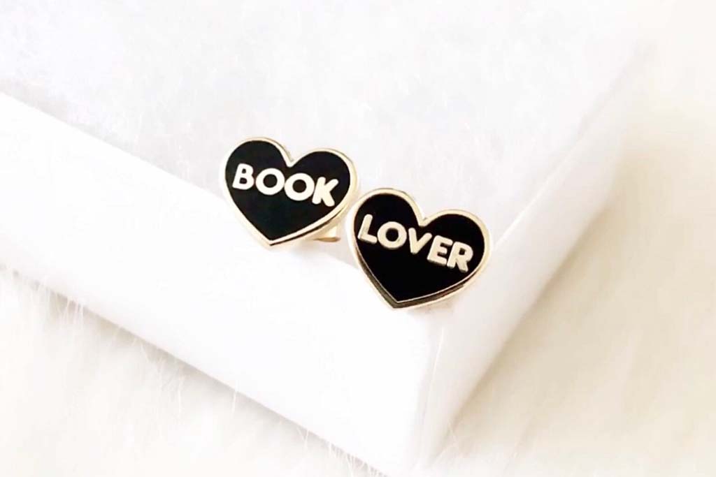 Black heart-shaped earrings with the words "book" and "lover" on them. By mysecretcopy.
