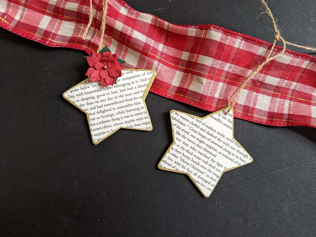 Two gold star-shaped ornaments with book page images on them. By AustenesqueCo