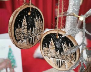 Round wooden ornament with night sky and image of Hogwarts castle by EmmaBeebeeArt