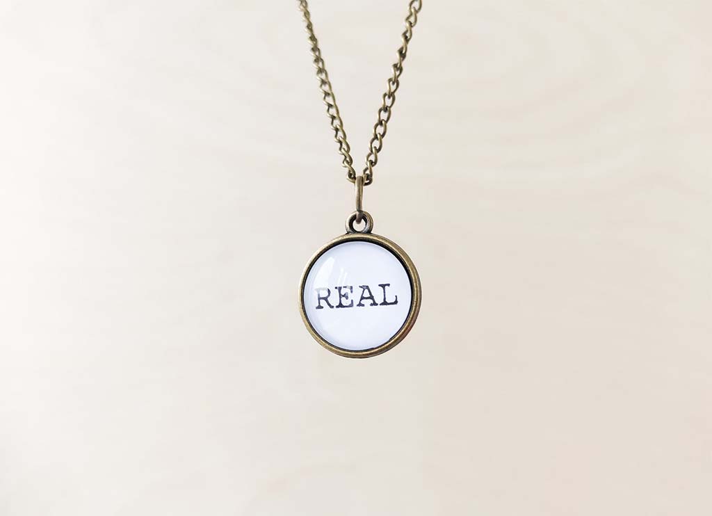 Round pendant on a chain that says "Real" by BeeHappyShop