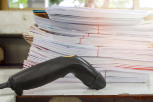 Handheld barcode scanner in front of a stack of papers