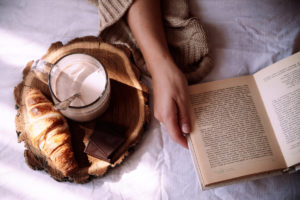 Flatlay featuring an open book, hot chocolate, and a croissant