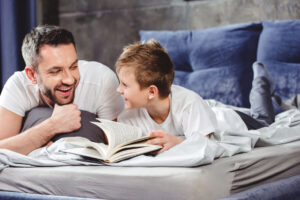 A father and son reading a book together on a bed