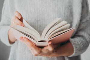 Girl in gray sweater holding an open book