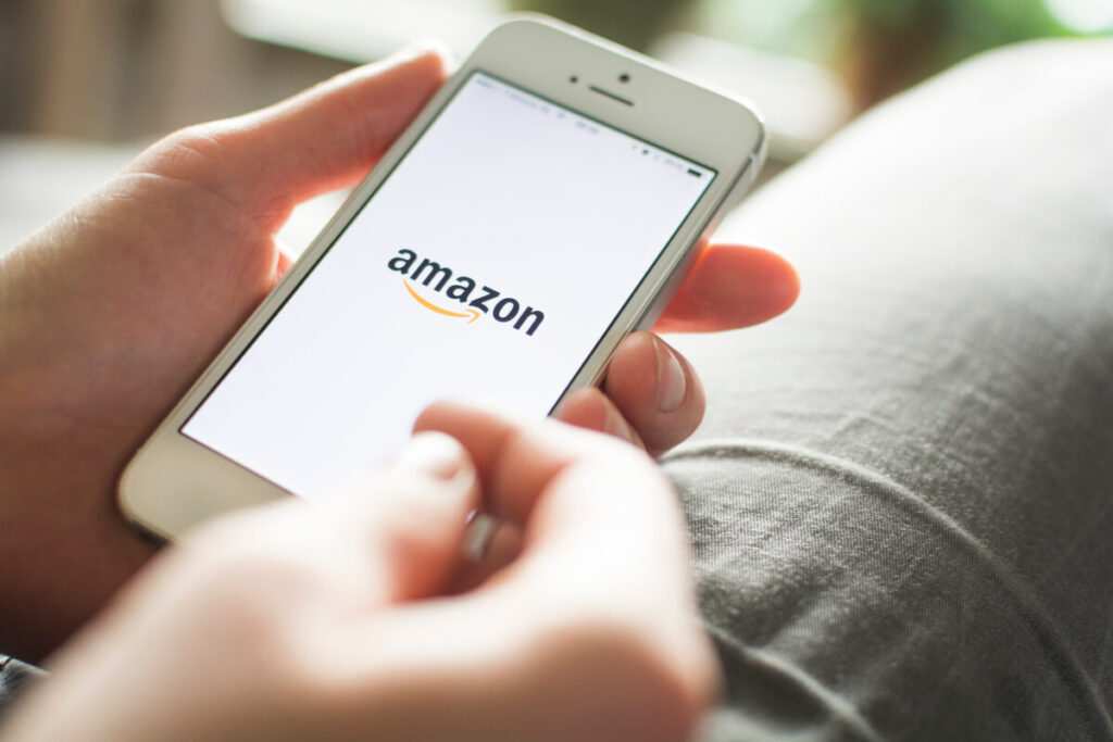 Man holding a phone with the Amazon logo on the screen