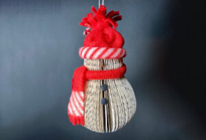 Snowman made out of book pages with knit hat and scarf