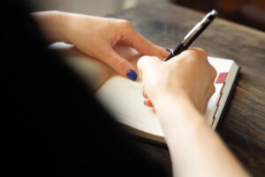 Woman holding a pen and writing in a journal