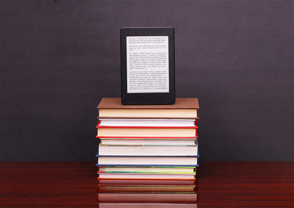 A kindle sitting on top of a stack of books