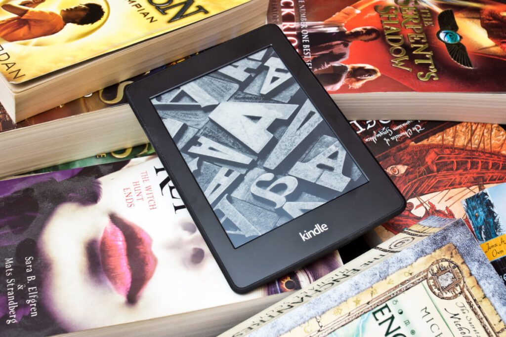Kindle e-reader sits on top of a pile of books
