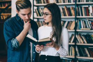 A man and a woman looking thoughtfully at the book the woman is holding