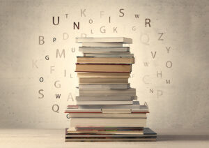 Stack of books with flying letters in the air surrounding them