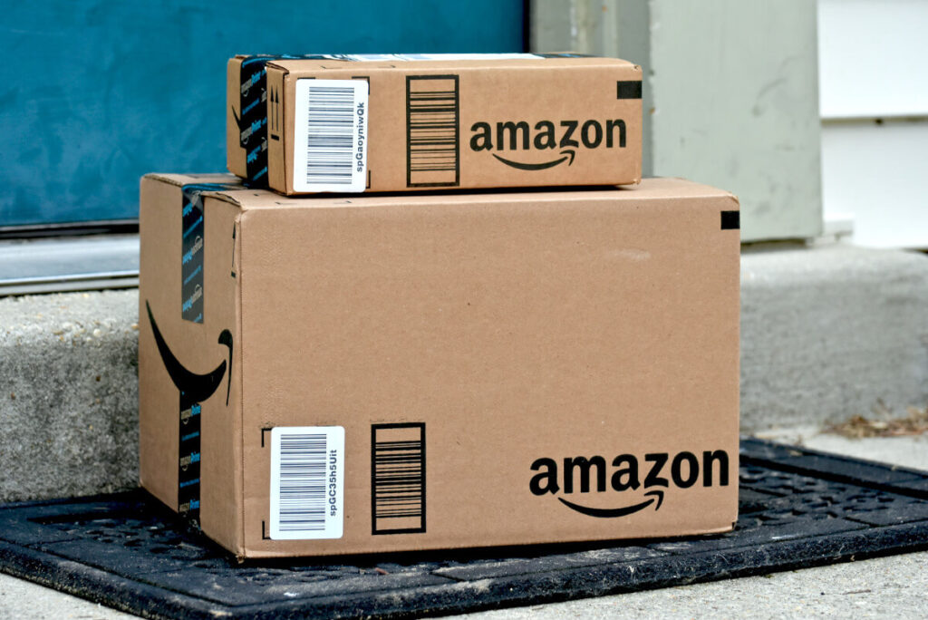 Two Amazon boxes stacked on top of each other on a mat on a front porch