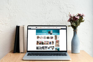 Amazon website open on a laptop sitting on a desk with books and flowers
