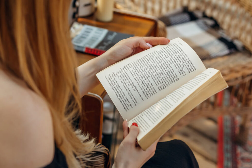 Woman with red nail polish holds open a book to read